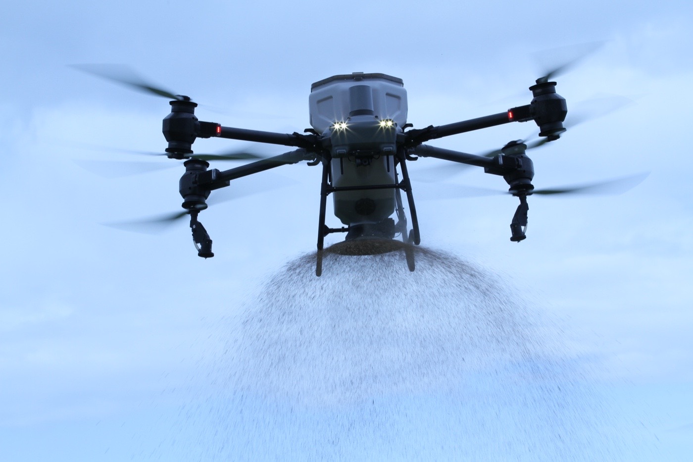Agricultural drone spreading granules — visible spread cone